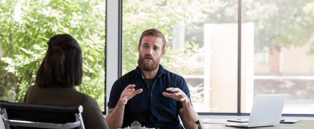 A man and woman talking at a table in an office with a therapist.