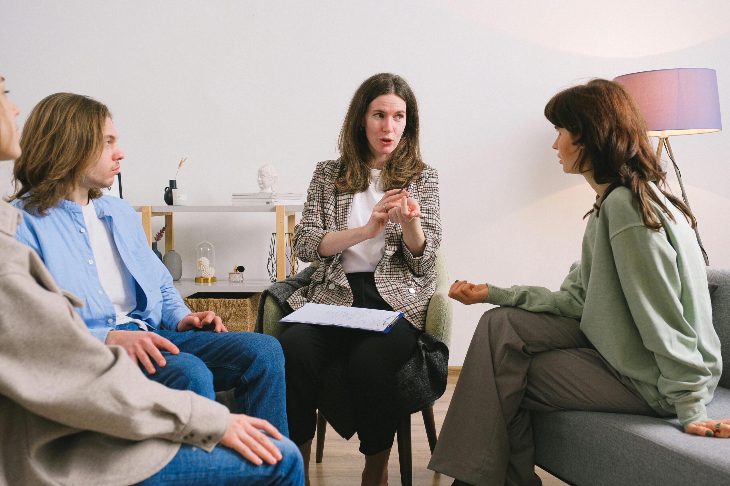 A group of women sitting in a circle in an office with a therapist facilitating.